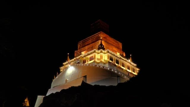 Looking up at the Thai temple brightly lit at night