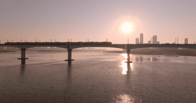 Train crossing a bridge over a river at sunset