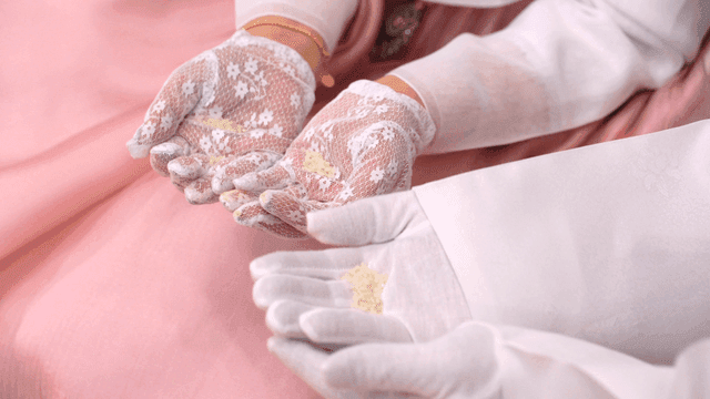 Hands in traditional attire holding rice