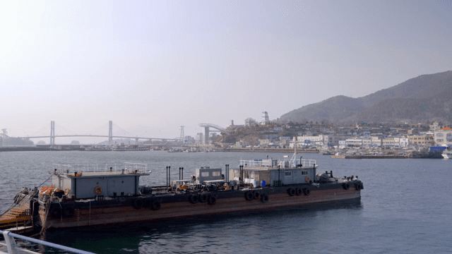 산과 건물들이 있는 잔잔한 바다의 바지선