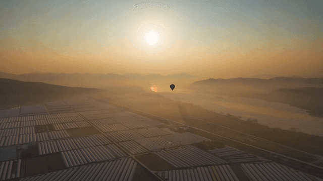 A hot air balloon over fields at sunset