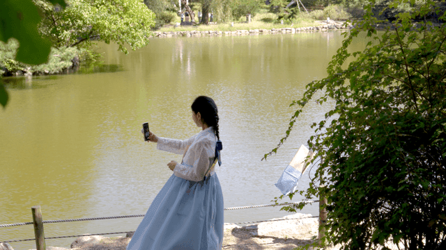 호숫가에서 셀카를 찍는 한복 입은 여성