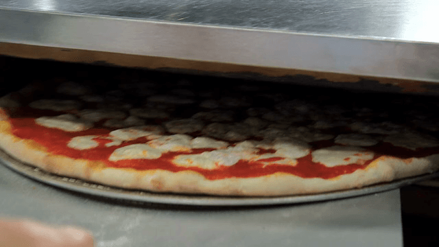 Pizza being placed in an oven