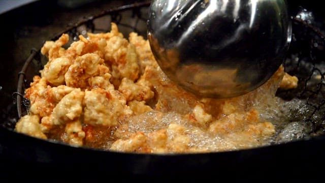 Frying meat in hot oil with a strainer