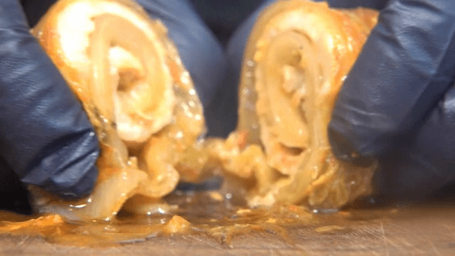 Kimchi wrapped pork being sliced on a cutting board