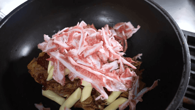 Pork neck bones in pot and crunchy bones going up over rice cakes