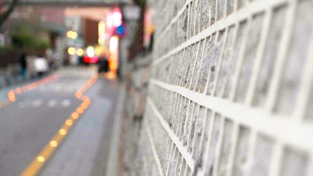 Alley with people walking next to a stone wall