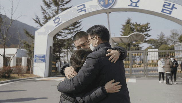 Family sitting and crying at entrance to army training camp.