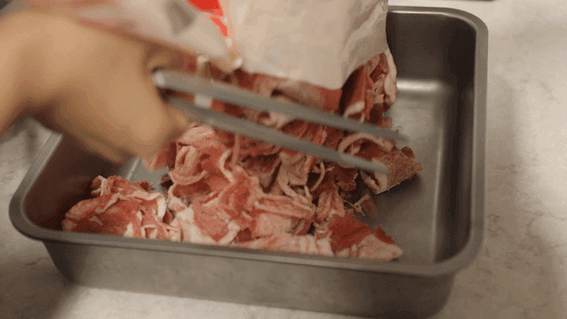 Hand placing frozen meat on tray