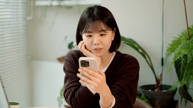Young woman resting her chin on her hand and looking at her phone