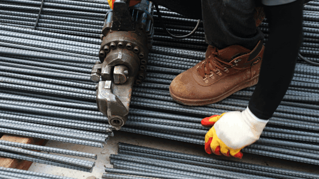 Worker cutting steel bars with a machine