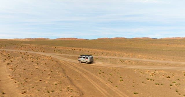 Van driving through a vast desert landscape