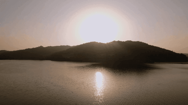 Sunrise over tranquil lake with mountains in background