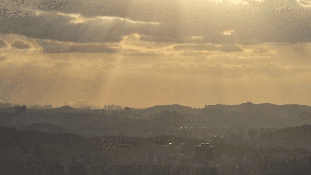 도시 위로 구름 사이로 비치는 햇빛