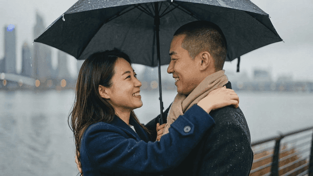 Couple embracing under an umbrella by the river