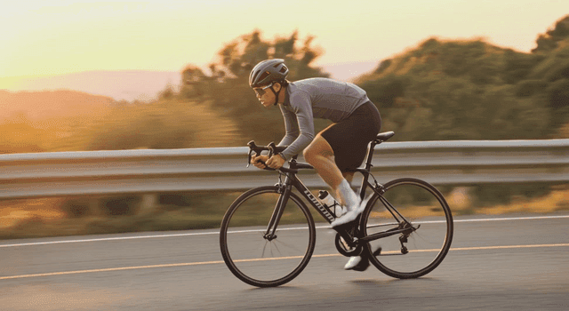 Cyclist riding on a road during sunset