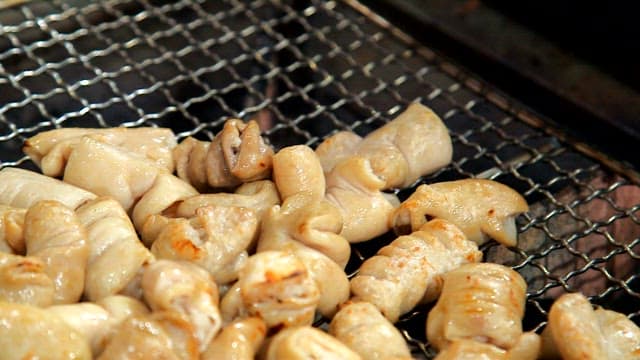 Grilling pork intestines on a grill