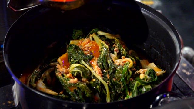 Putting seasoning broth in a pot with napa cabbage