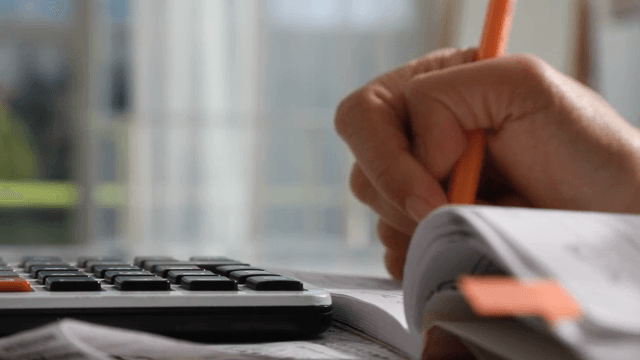 Hand using a calculator and writing notes