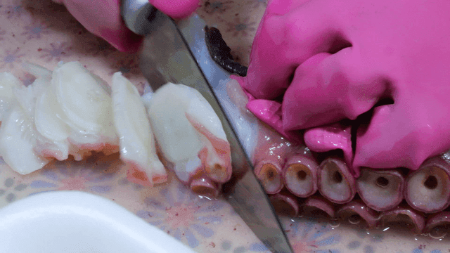 Sight of cutting boiled octopus legs with knife
