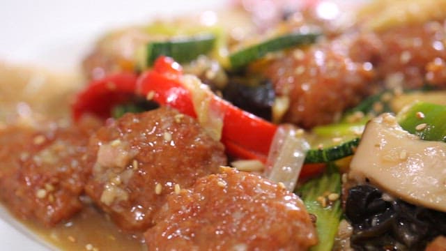 Appetizing stir-fried meatballs and vegetables sprinkled with sesame seeds