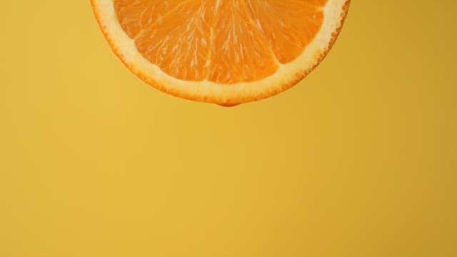 Scene with juice dripping from an orange on a yellow background