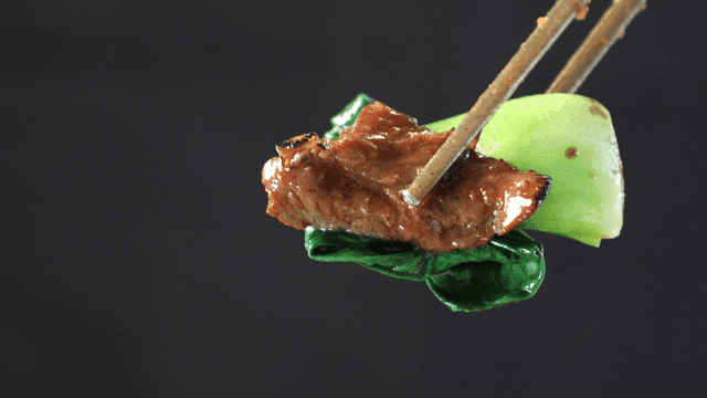 Bok choy and grilled meat picked up with chopsticks