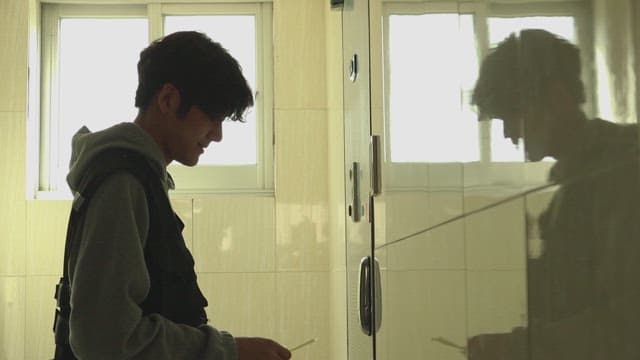 어두운 복도에서 현관문에 전단지를 붙이는 남자