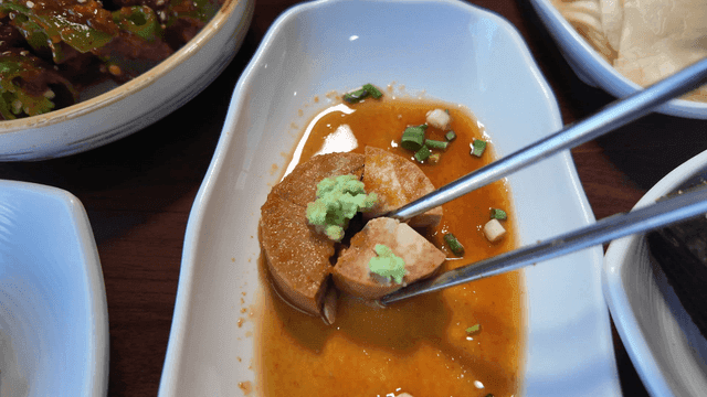 Eating monkfish liver with chopsticks on table