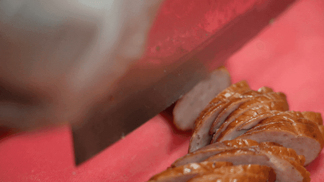 Sausage being cut on red cutting board