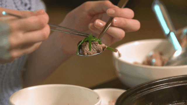 Woman eating duck soup with spoon