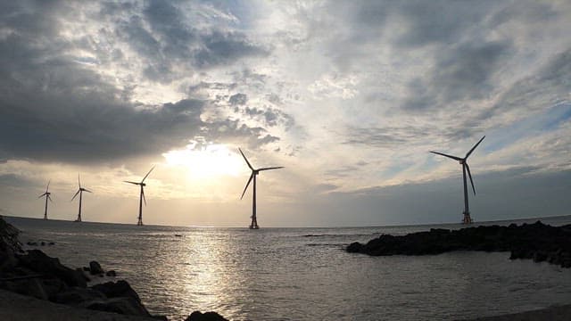 Sunset on the coast with wind turbines spinning