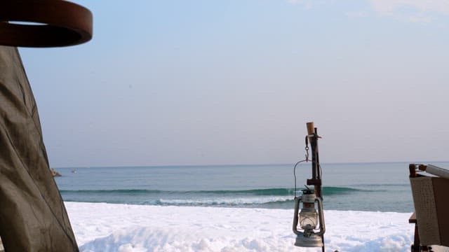 Snowy beach with a camping lantern during a calm morning