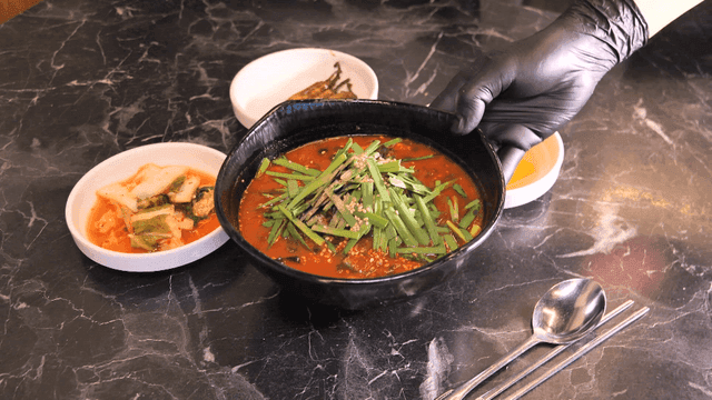Korean side dishes and spicy sundubu jjambbong on table