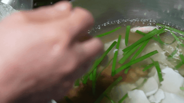 Hands preparing handmade dumpling dough to be added to clear broth
