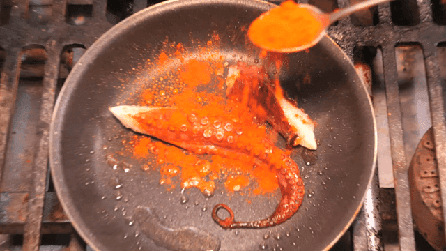 Octopus legs cooked in pan with paprika spices sprinkled on them