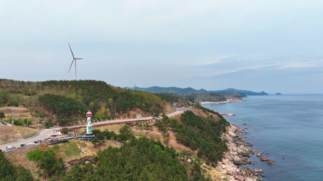 Coastal road with a lighthouse and wind turbine