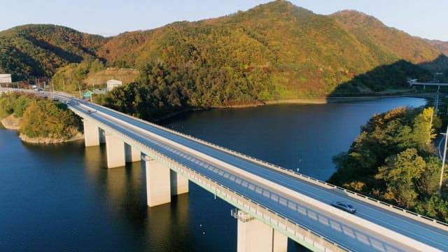 경치 좋은 강 위의 다리를 달리는 차량들