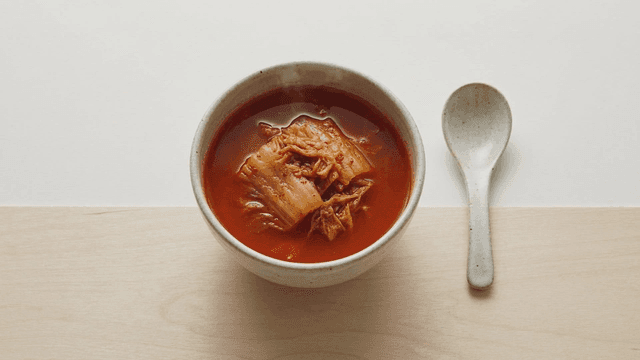 Kimchi stew in a ceramic bowl with a spoon