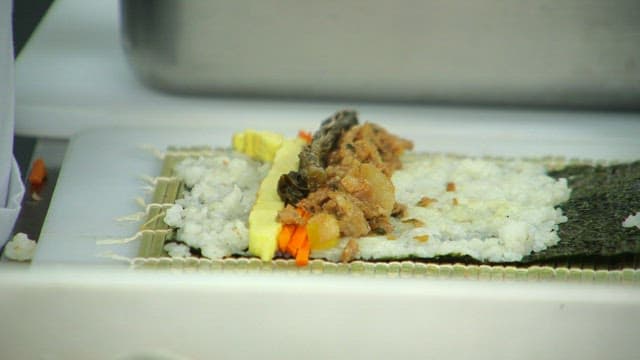 갓을 넣은 김밥을 준비하는 비닐장갑 낀 손