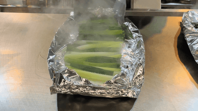 Steamed green onion in foil on griddle