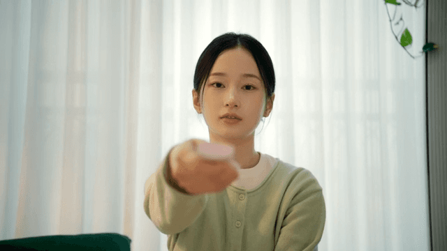 Woman sitting on living room sofa using remote control