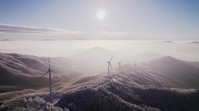 Wind Generators on Misty and Snowy Mountain in the Morning