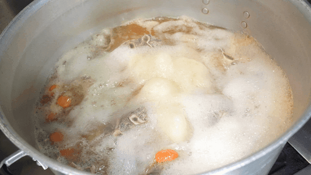Large pot of broth boiling on stove