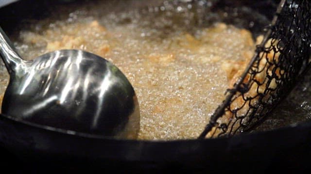 Frying meat in hot oil with a strainer