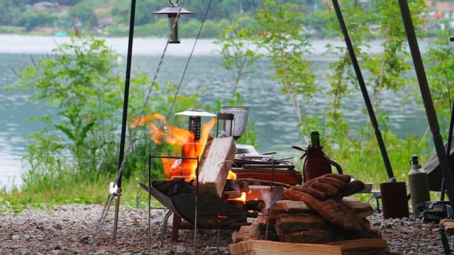 Camping by the lakeside with a campfire burning in brazier brightly