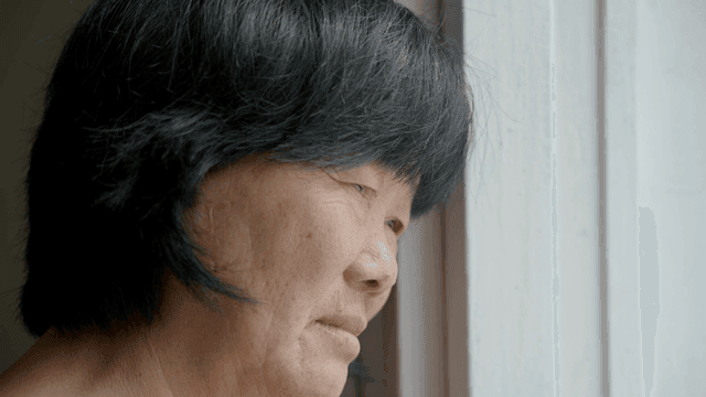 An elderly woman gazing out the window