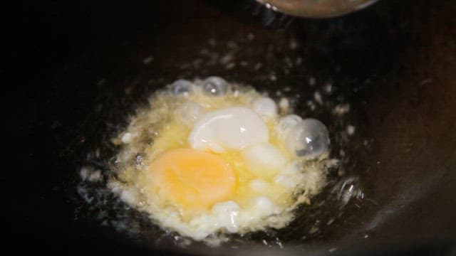 Egg frying in a hot pan with hot oil