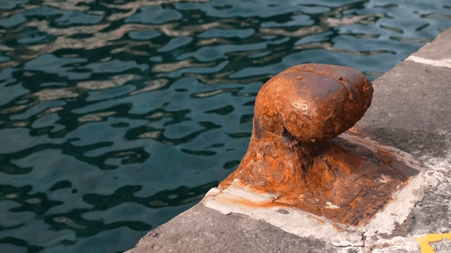 Rusty bollard by the water's edge