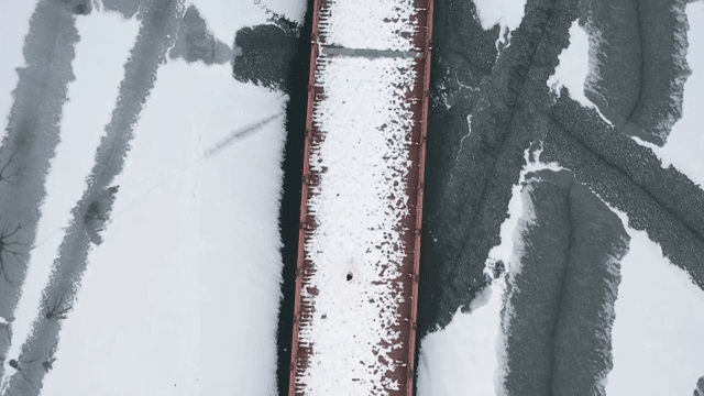 Person walking on a snow-covered bridge over a frozen lake
